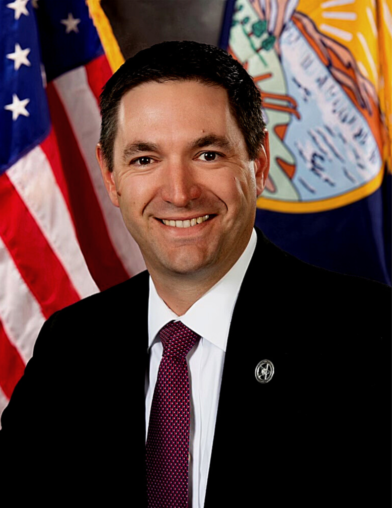 Attorney General Austin Knudsen in suit before U.S. and Montana flags